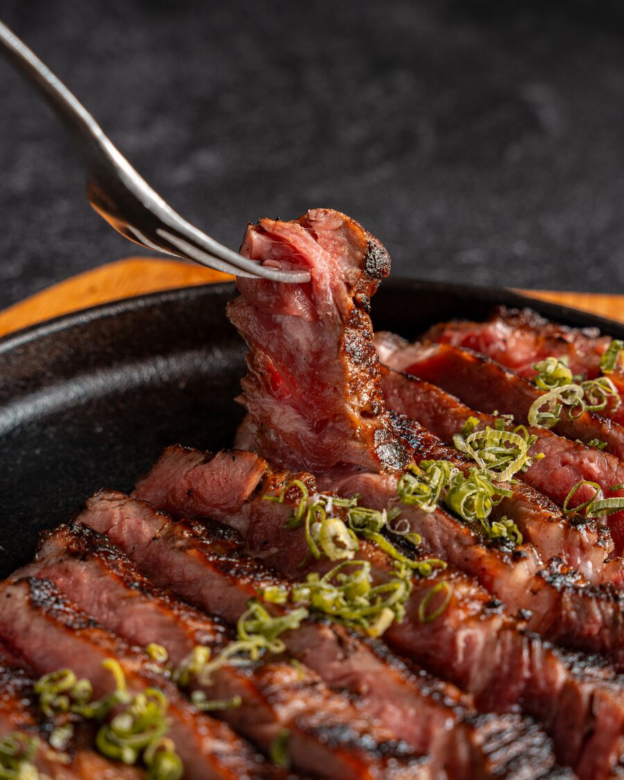 Tenedor levantando un trozo de carne a la brasa