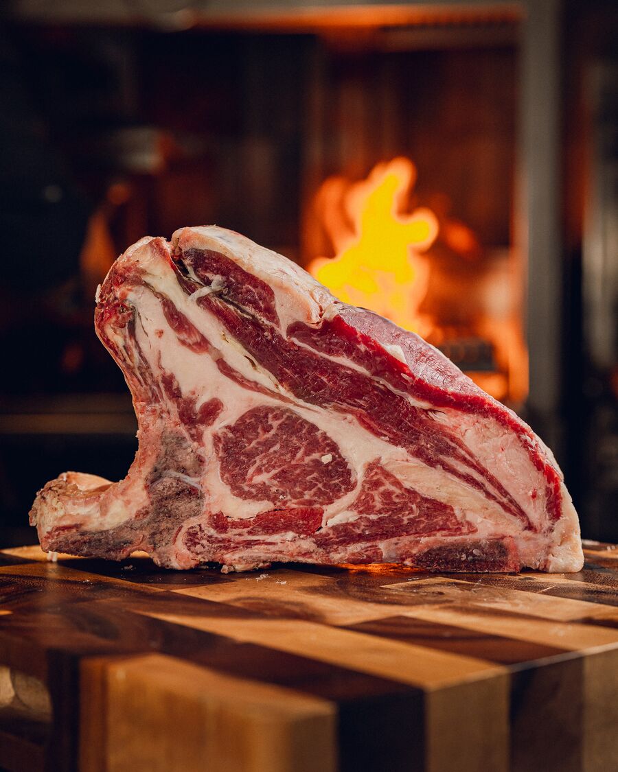 Tomahawk crudo sobre la tabla con el fuego detrás